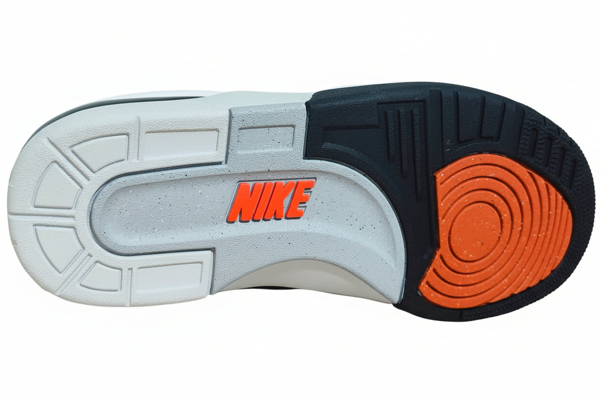 Close-up of the outsole of a Nike sneaker, showing a white and black tread pattern with a bright orange circular section and orange Nike logo, resting on an orange surface.